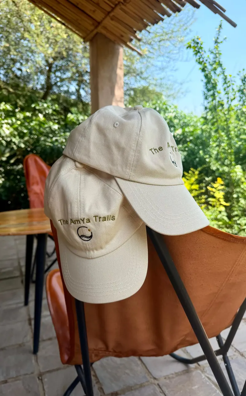 The AmYa Trails embroidered caps resting on a leather chair outdoors